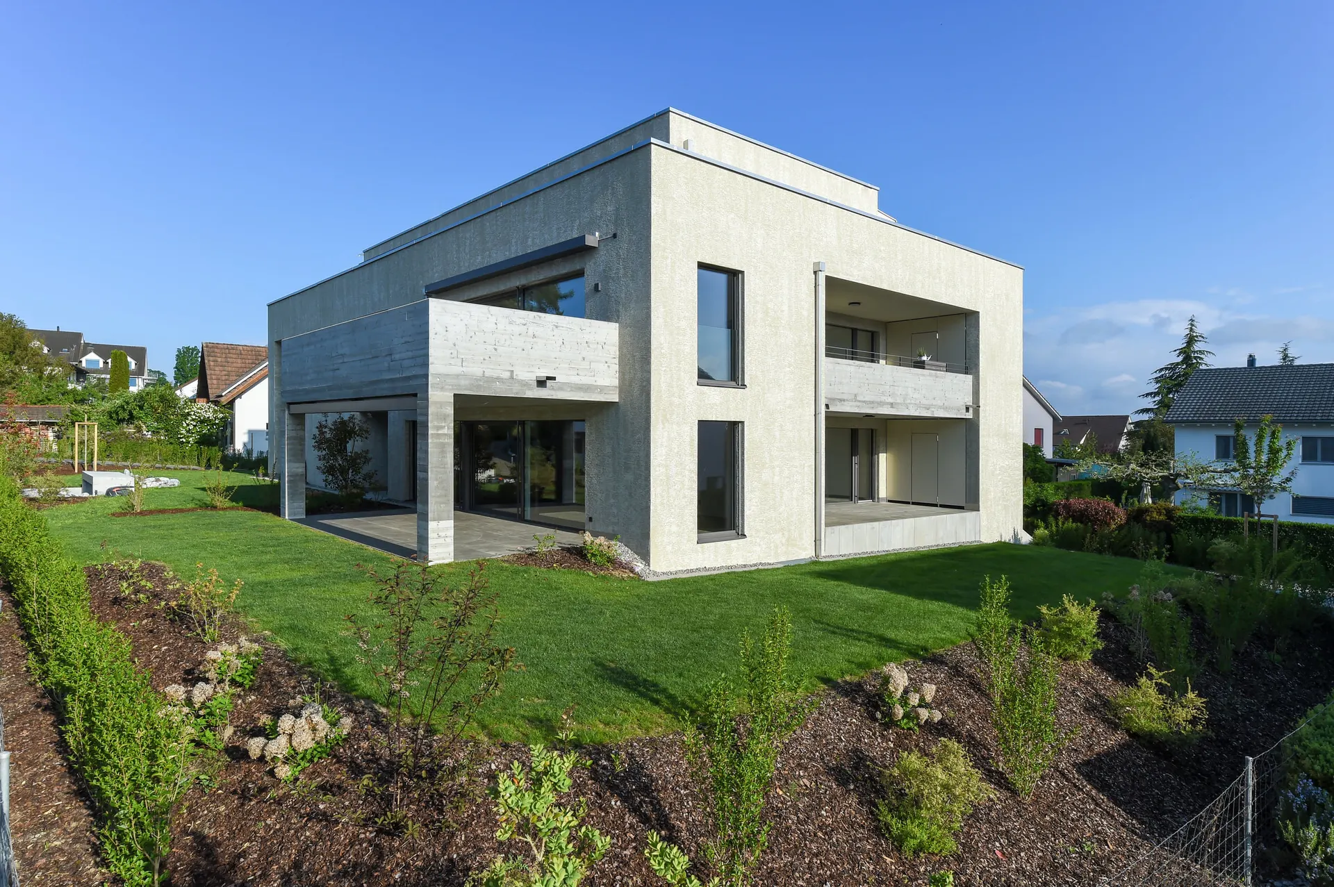 Seitliche Gartenansicht mit Eckverglasung, Loggien und Rasenflächen.