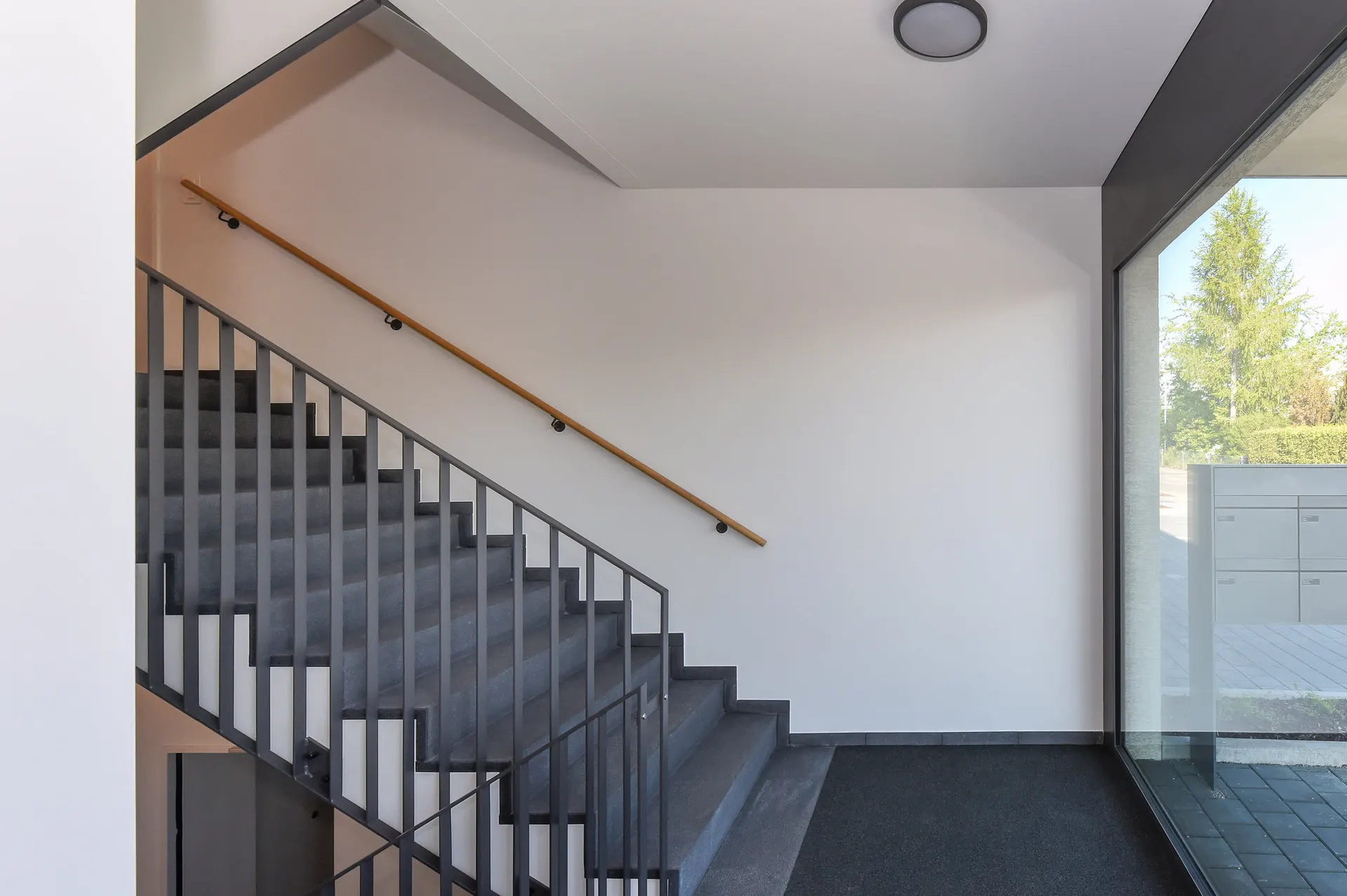 Gemeinsames Treppenhaus mit Metallgeländer und Tageslicht am Eingang.