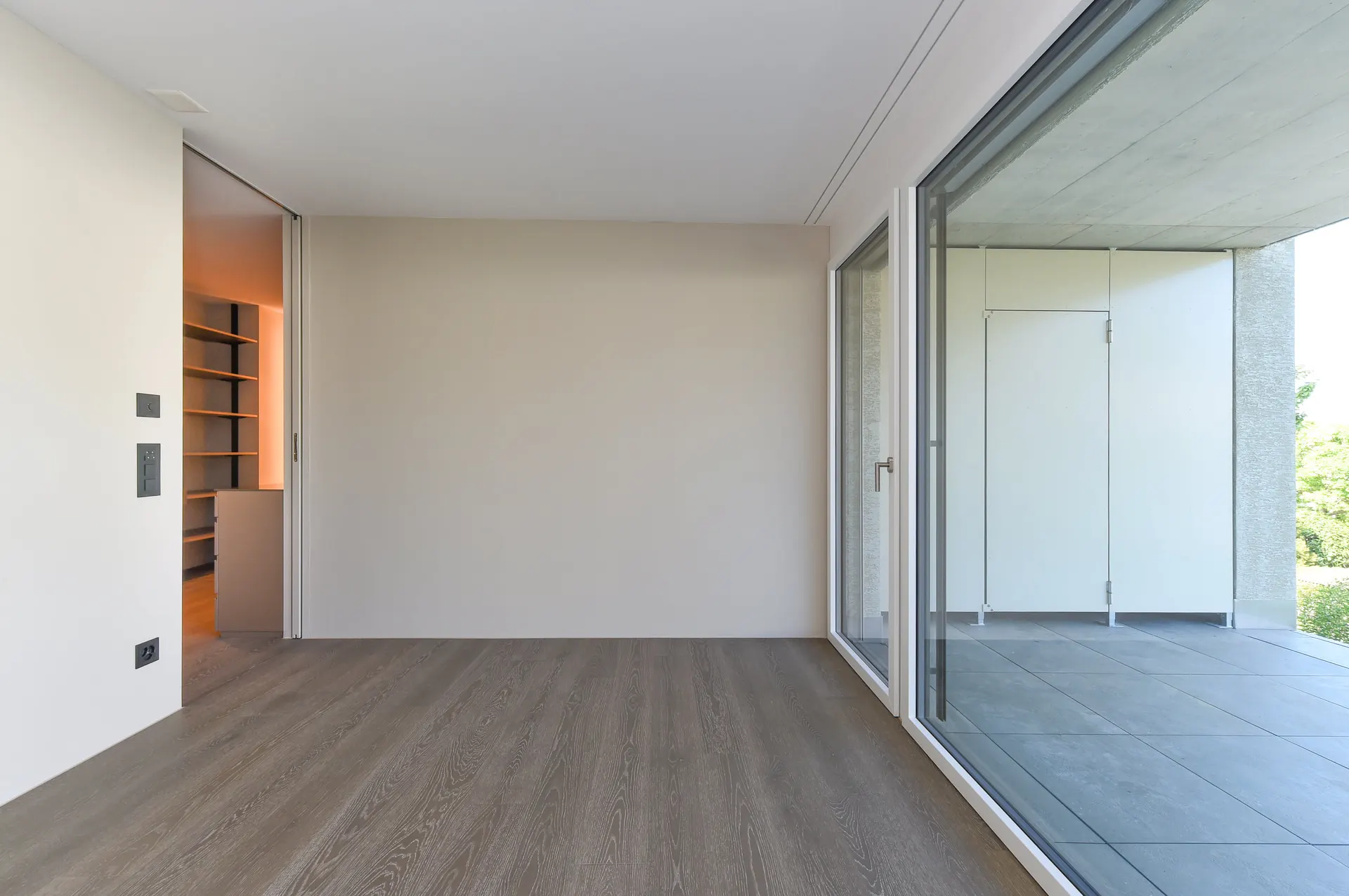 Wohnraum mit Holzfussboden am Übergang zur geschützten Loggia.