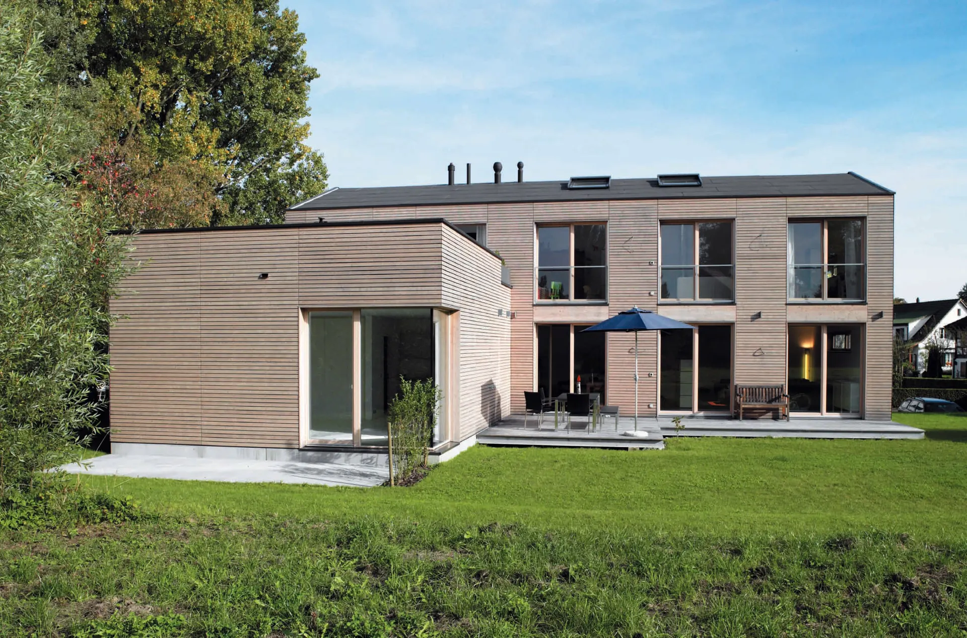 Historische Presseaufnahme der vollständigen Gartenseite mit Holzfassade, Anbau und Terrasse.