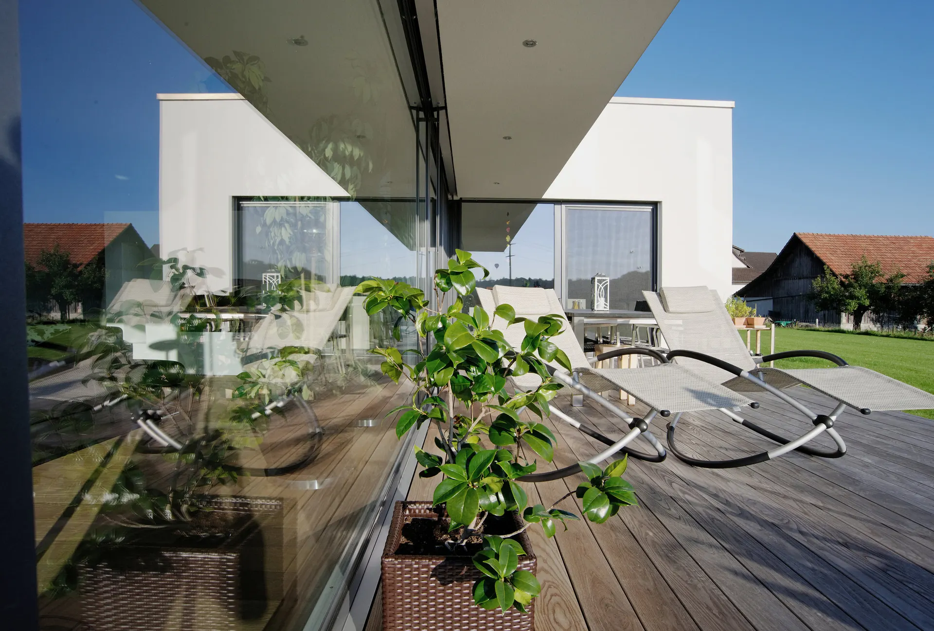 Blick entlang der raumhohen Verglasung über die geschützte Terrasse.