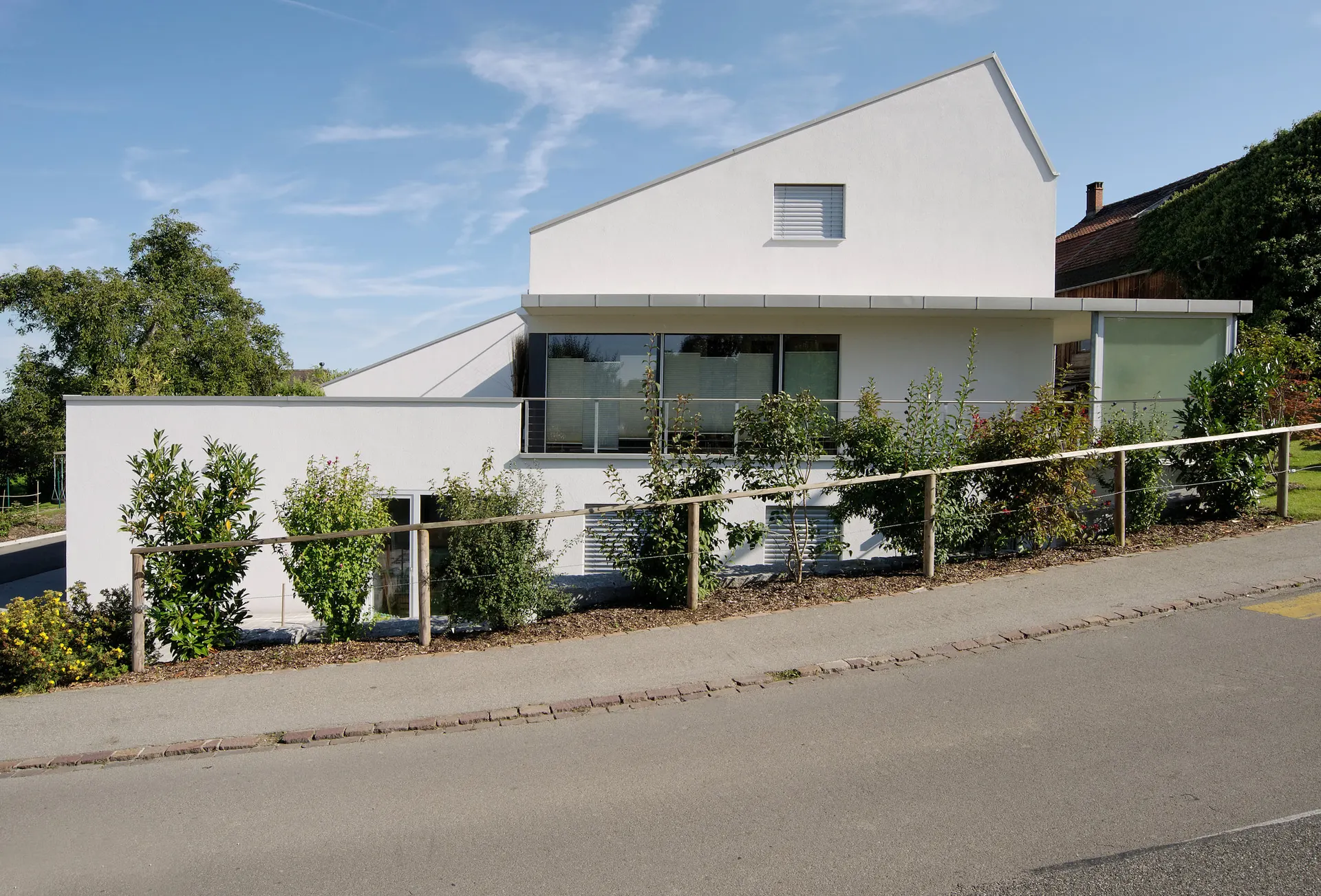 Seitliche Gartenansicht mit Terrasse und ansteigendem Dach.