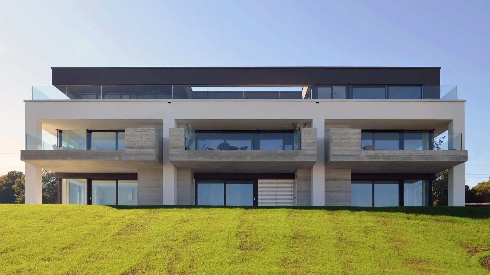 Gartenansicht eines Mehrfamilienhauses in Kreuzlingen mit tiefen Terrassen und zurückgesetztem Attikageschoss.
