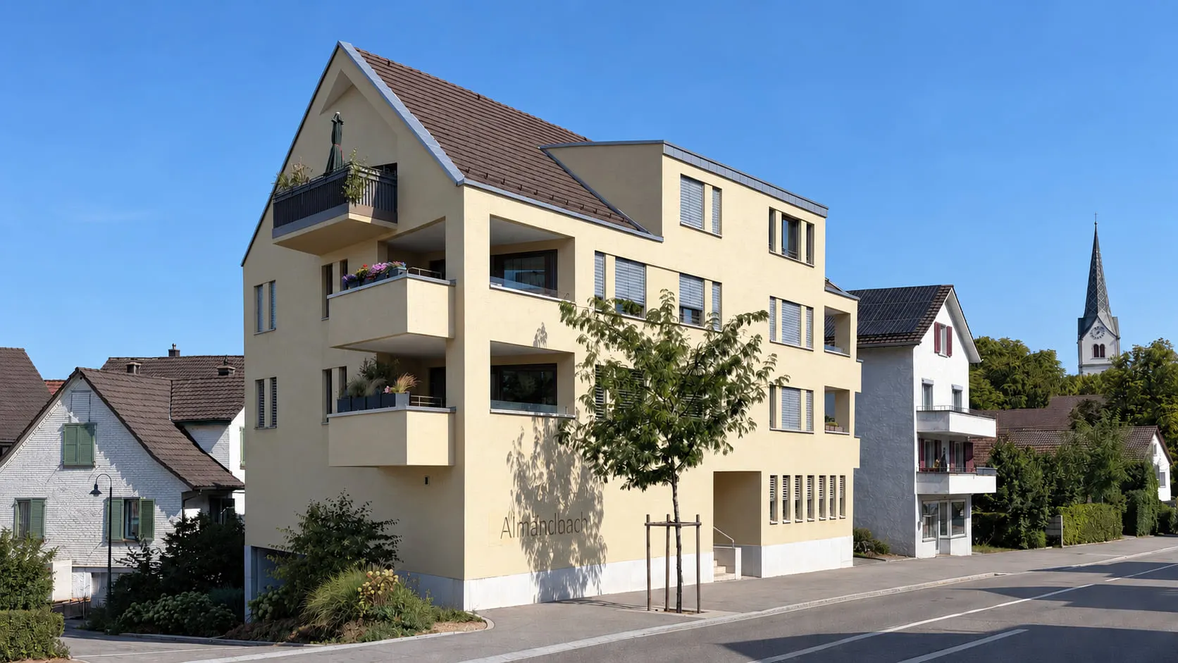 Mehrfamilienhaus Almändbach in Tägerwilen mit warmfarbener Putzfassade, geneigtem Dach und gestaffelten Balkonen im Dorf.