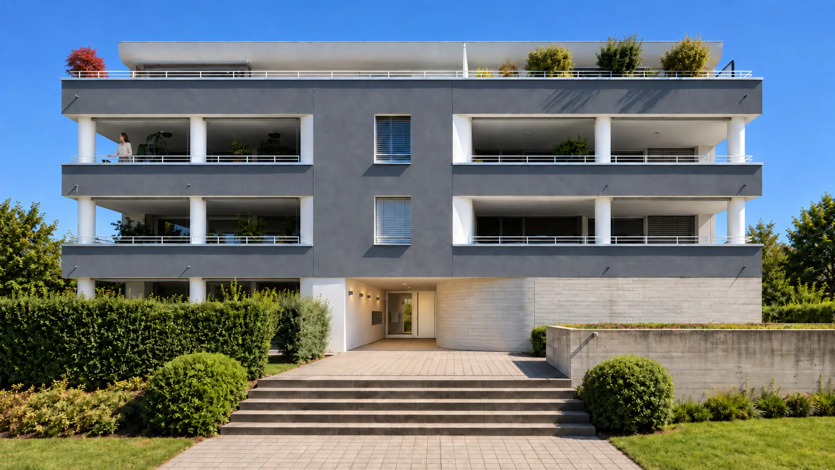 Frontale Ansicht von Sea Breeze mit dunklen Fassadenbändern, zurückgesetzten Loggien, Bepflanzung und mittigem Eingang.